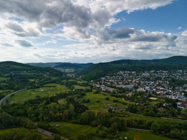 Şehir ve tepeleri olan yemyeşil bir vadinin havadan görünüşü.