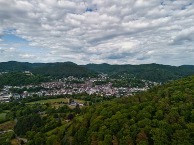 Şehir ve tepeleri olan yemyeşil bir vadinin havadan görünüşü.