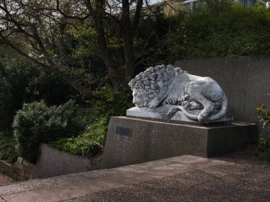 Parkta uzanan bir aslan figürü merdiven kenarında.