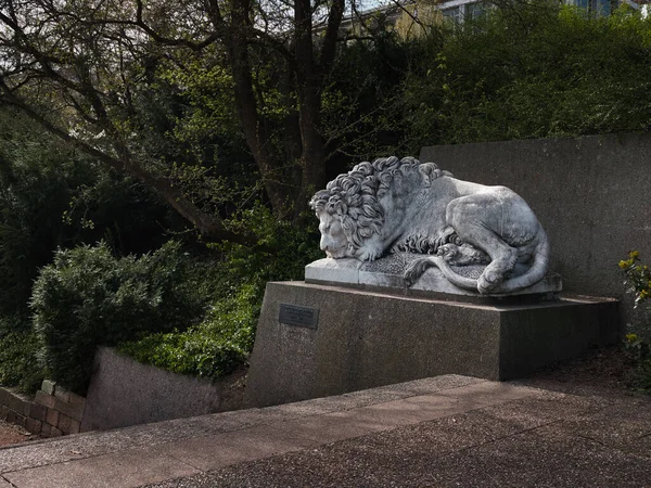 Parkta uzanan bir aslan figürü merdiven kenarında.