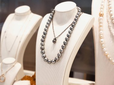 Bir kuyumcuda inci kolyelerin beyaz stantlarda sergilenmesi..