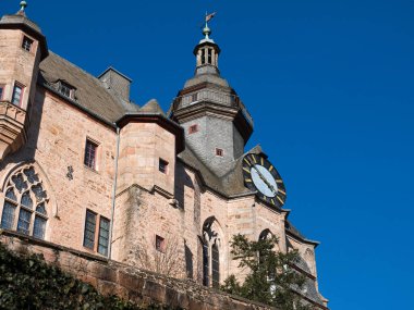 Mavi gökyüzüne karşı saat kulesi olan tarihi taş kale.