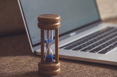 Arka planda dizüstü bilgisayarlı kum saati bitiyor. Görünüşte.