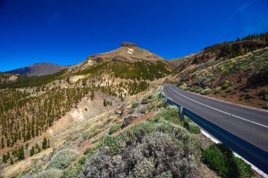 Teide Dağı 'ndaki boş yol, arka plandaki vadi, mavi gökyüzü.