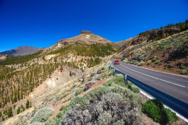 Volkanik Teide 'de kırmızı araba yol manzarası ve doğa 2 boyunca sürüyor.