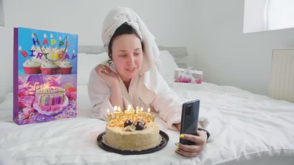 Młoda dziewczyna na łóżku hotelowym, komunikuje się i świętuje urodziny online — Wideo stockowe