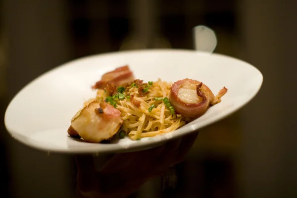 Bacon wrapped scallops and fettuccini on a white plate — Stock Photo, Image