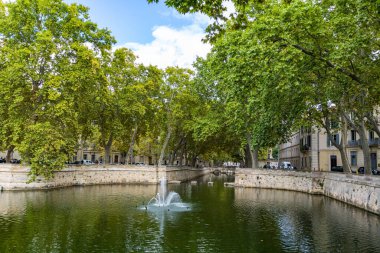 Nimes 'teki ağaçların altında Kanal de la fontaine (Occitanie, Fransa)