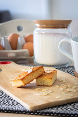 Bademlerle süslenmiş kesme tahtasına serpiştirilmiş altın sarısı finansör keklerinin yakın çekimi.