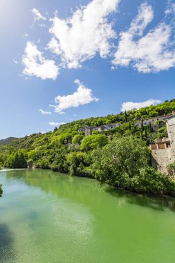 Vidourle (Occitanie, Fransa) kıyısındaki ortaçağ köyü Sauve 'nin eski evleri ve orman manzarası)