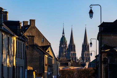 Bayeux 'nun Notre-Dame Katedrali ve şeffaf merkezi fener kulesi günün sonunda bir şehir caddesinden görüldü.