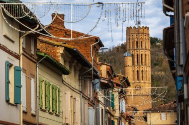 Rue Mages 'dan Montesquieu-Volvestre' nin merkezindeki Saint Victor Kilisesi 'nin kırmızı çan kulesine doğru görüş.