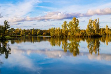 Uzun vadede Sabatouse Gölü 'nün sakin sularındaki sonbahar ağaçlarının yansımaları.