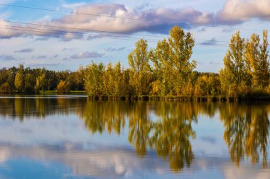 Uzun vadede Sabatouse Gölü 'nün sakin sularındaki sonbahar ağaçlarının yansımaları.