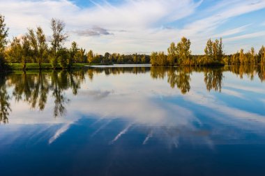 Uzun vadede Sabatouse Gölü 'nün sakin sularındaki sonbahar ağaçlarının yansımaları.