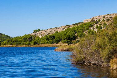 La Clape Massif 'in bir parçası olan Les Auzils' in kireçtaşı kayalıkları Gruissan gölüne bakıyor.