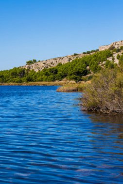 La Clape Massif 'in bir parçası olan Les Auzils' in kireçtaşı kayalıkları Gruissan gölüne bakıyor.