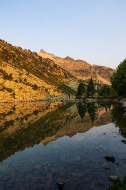 Göller, yüksek dağlarla çevrili. Neouvielle Doğa Koruma Alanı 'nda doğan güneşle aydınlanan göller.