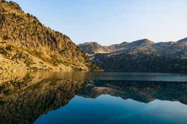 Güneş doğarken Aubert Gölü 'nün panoramik manzarası Neouvielle Doğa Rezervi' nin dağlarını yansıtıyor.