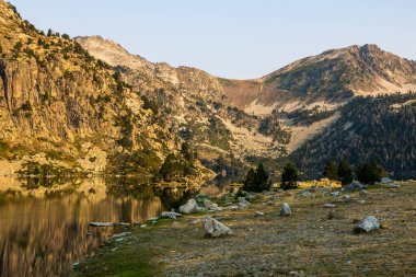 Güneş doğarken Aubert Gölü 'nün panoramik manzarası Neouvielle Doğa Rezervi' nin dağlarını yansıtıyor.