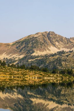 Güneş doğarken Aumar Gölü 'nün panoramik manzarası Neouvielle Doğa Rezervi' nin dağlarını yansıtıyor.