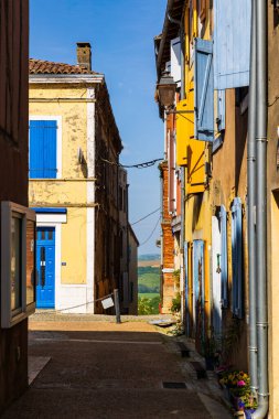 Carla-Bayle köyündeki bir ara sokaktan Leze vadisindeki tepelerin tarım manzarası.