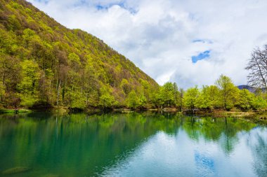 Baharda Bethmale Gölü, yemyeşil bir ormanla çevrili. Gölün yeşil sularına yansıyor.