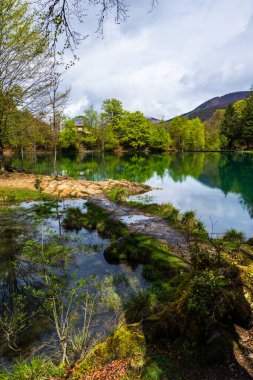 Baharda Bethmale Gölü, yemyeşil bir ormanla çevrili. Gölün yeşil sularına yansıyor.
