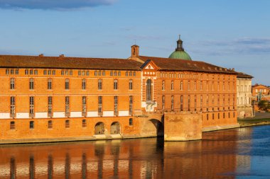 Toulouse 'daki Hotel-Dieu Saint-Jacques' ın cephesi, UNESCO Dünya Mirasları listesine işlenmiş bir anıt, sabah ışığı altında Garonne rıhtımlarından görülüyor.