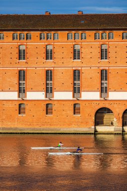 İki kürekçi sandallarıyla Toulouse 'daki Saint-Jacques Oteli' nin önündeki Garonne 'da yol alıyorlar.