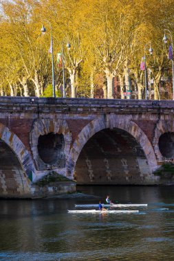 İki kürekçi, Pont Neuf yakınlarındaki Toulouse 'da Garonne nehrinde yol alıyorlar.