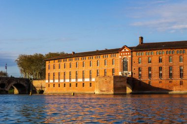 Toulouse 'daki Saint-Jacques Oteli' nin cephesinde UNESCO Dünya Mirasları listesine işlenmiş bir anıt sabah ışığı altında Garonne nehrinin sularına yansıyor.