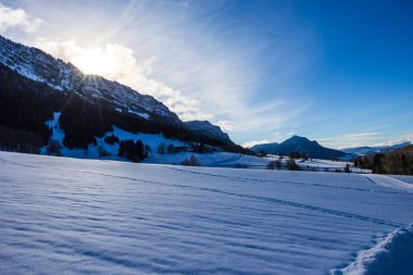 Merkez Vercors 'un yüksek kireçtaşı kayalıklarının üzerindeki güneş Rencurel' deki Col de Romeyere 'deki küçük Coulmes kayak merkezinden görüldü.
