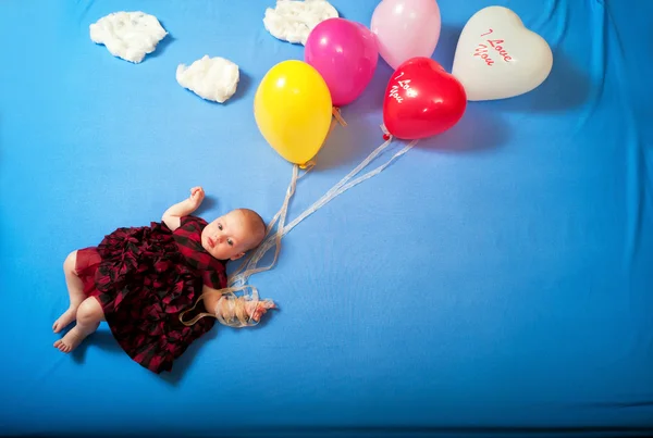 Bebê voa em balões nas nuvens deitadas na cama — Fotografia de Stock