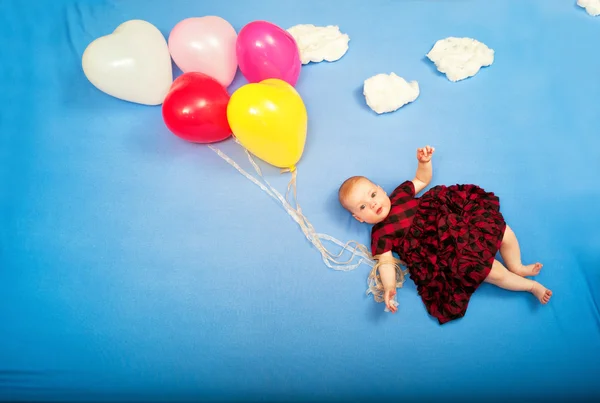 Bebê voa em balões nas nuvens deitadas na cama — Fotografia de Stock