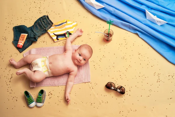 Çocuk yalanlar üzerine bir havlu plaj ve bir kokteyl içme