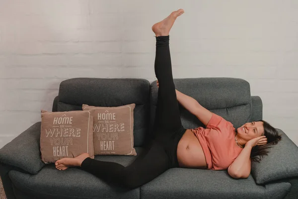 Hamile bir kadın kanepenin üzerinde geriniyor. Hamilelik sırasındaki sağlık kavramı. Boşluğu kopyala