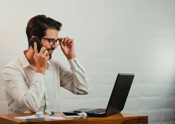Gözlüklü Latin adam çalışıyor. Laptop ve cep telefonu kullanarak. Ev konseptinde çalış. Boşluğu kopyala.
