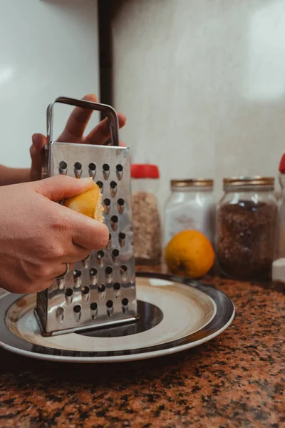 Bir kadının ellerinin portakalı tabağın üstünde ızgara yaparken dikey çekimini kapat. Sağlıklı ve ev yapımı gıda konsepti