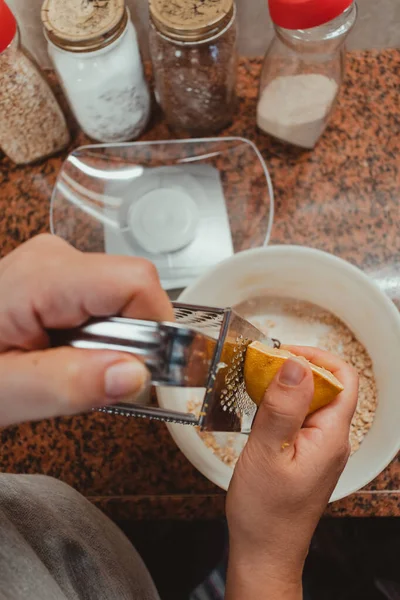 Bir kadının ellerinin portakalı ızgaraya çevirdiği dikey çekim. Bu da kurabiyeye dönüşecek..