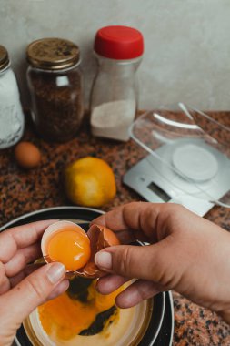 Kurabiye karışımına ekleyeceği yumurtayı kıran bir kadının yakın plan fotoğrafı. Sağlıklı yaşam ve ev yapımı gıda kavramı.