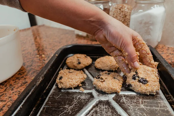 Pişirmek için tavaya çiğ kurabiye koyan bir kadının yakın çekimi.