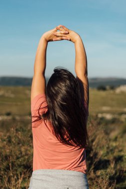 Yürüyüşten sonra esneme hareketleri yapan İspanyol bir kadının dikey yakın çekimi. Sağlık, spor ve doğa kavramı. Tanımlanamayan kişi
