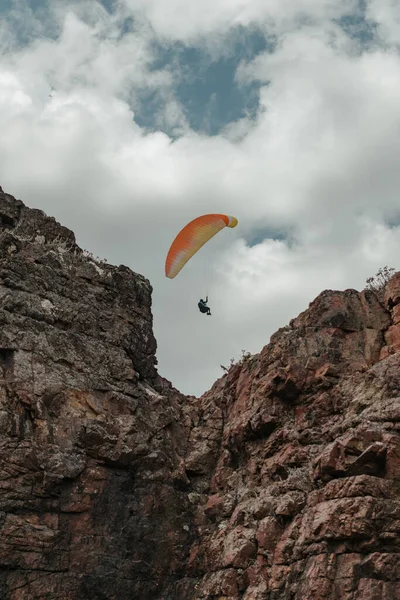 Vertical shot of a solo paraglider over a cliff