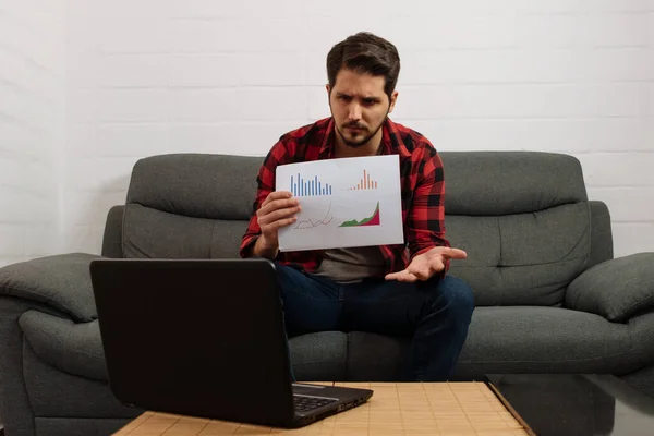 Kızgın Latin adam dizüstü bilgisayarda grafikler gösteriyor.