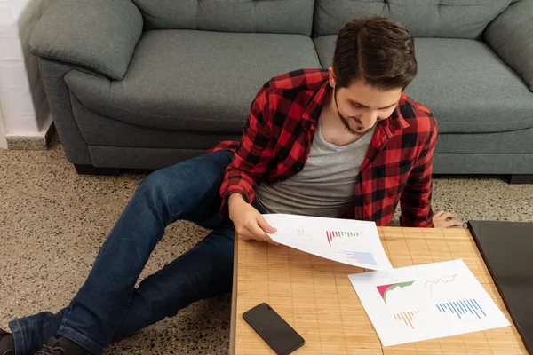 Latin adam oturmuş, grafiklere yakından bakıyor ve gülümsüyor.