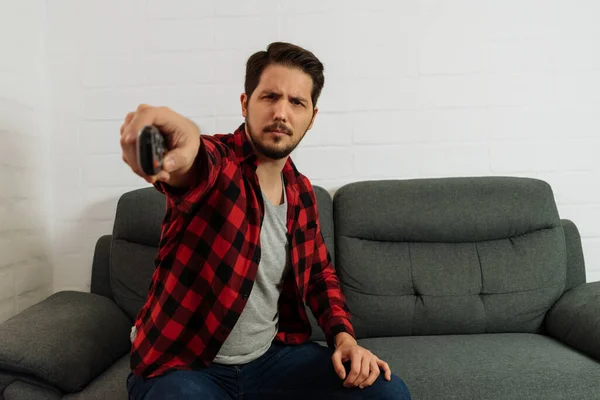 Konsantrasyon ifadesi olan Latin adam uzaktan kumandalı kanal değiştiriyor.