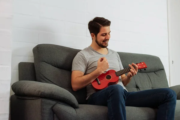 Latin adam içeride ukulele oynarken gülümser..