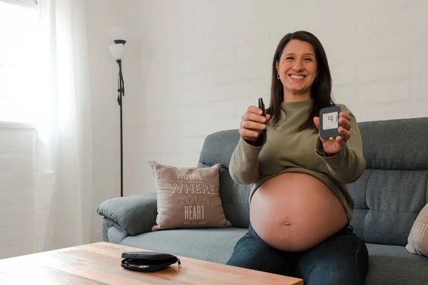 Hamile İspanyol kadın kameraya kan şekeri testinin sonucunu gösteriyor.