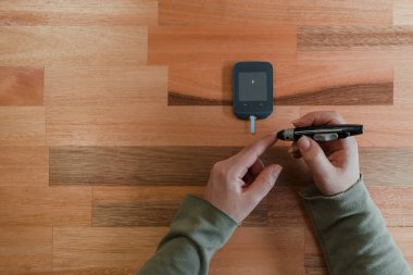 Elinde glukometre olan Latin bir kadının ellerinin üstünden.